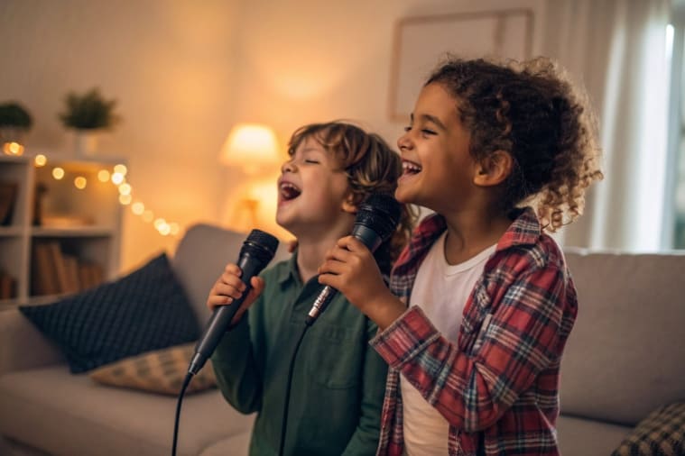 Two kids happily singing into a dual-microphone karaoke machine